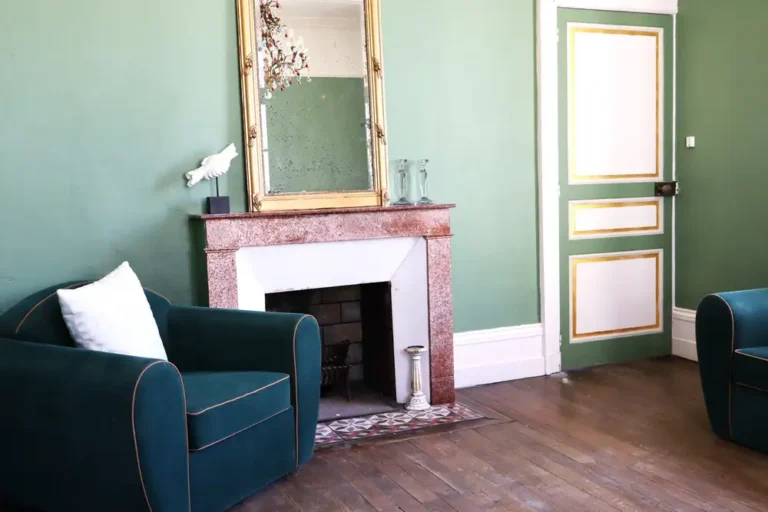 A green armchair in front of a mirror.