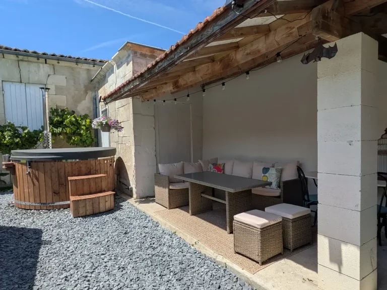 A covered outdoor dining area with a hot tub adjacent